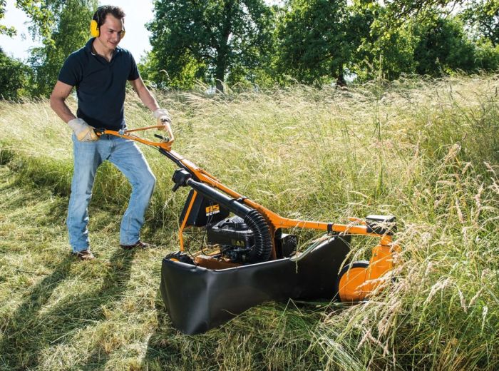 Ein Mann mäht mit einem AS Motor Wiesenmäher das Gras auf einer gepflegten Rasenfläche.