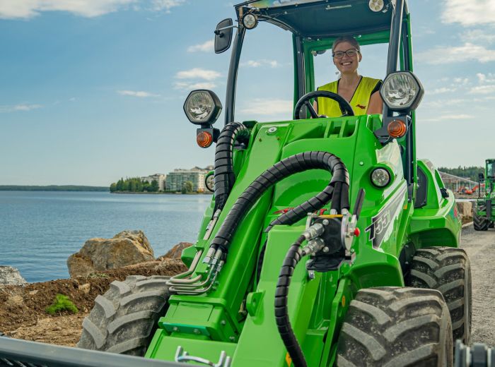Ein Mann fährt einen grünen Avant Lader-Traktor auf einer Straße