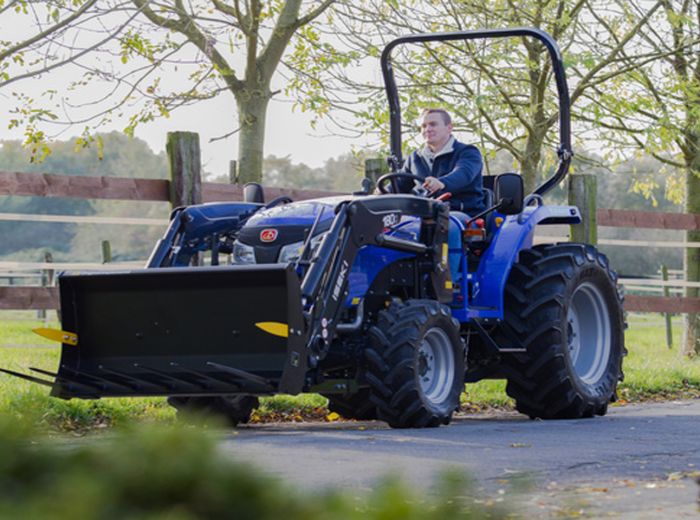 Ein Mann fährt einen blauen Avant-Traktor auf einer Straße