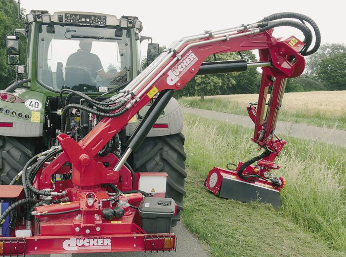 Landwirtschaftliche Maschine im Fokus – Traktor mit rotem Anbau in ländlicher Umgebung