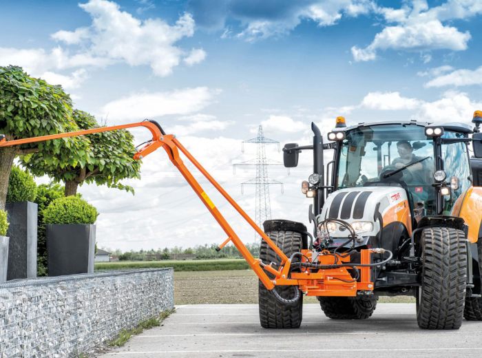 Ein Traktor mit einem großen orange-schwarzen Frontbereich, Modell Ecotech Giessarm GA3, auf einem Feld abgebildet