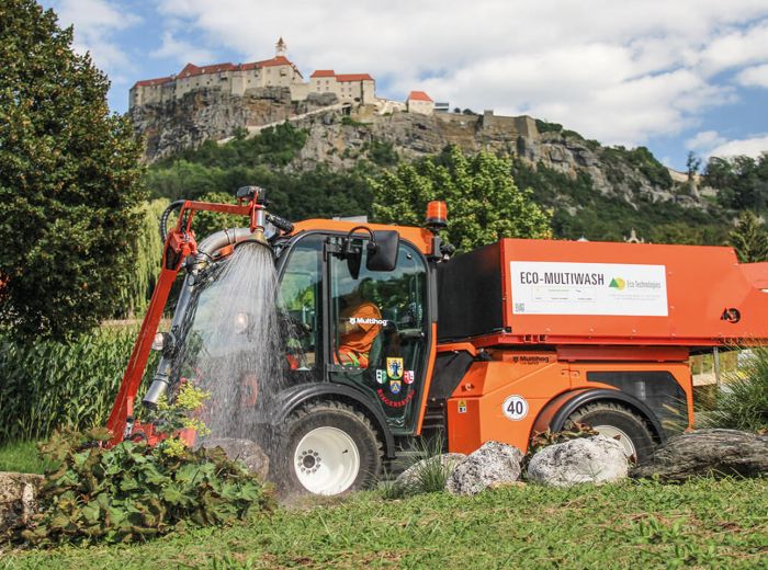 Ein Traktor mit dem Ecotech Giessarm Ga3 sprüht Wasser auf einen Hang zur Bewässerung der Pflanzen