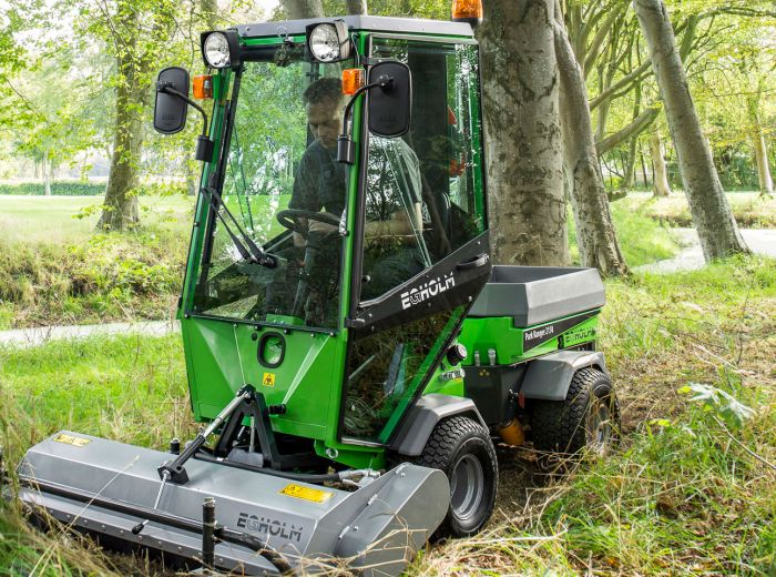 Ein Mann steuert eine grüne Egholm Action-Maschine durch einen Wald