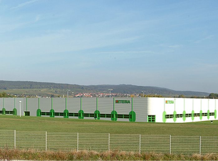 Etesia Firmengelände mit einem großen Gebäude, das von einem Zaun umgeben ist.