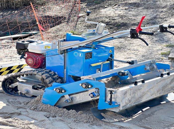 Eine blaue und gelbe Fiorentini Sandreinigungsmaschine auf sandigem Boden