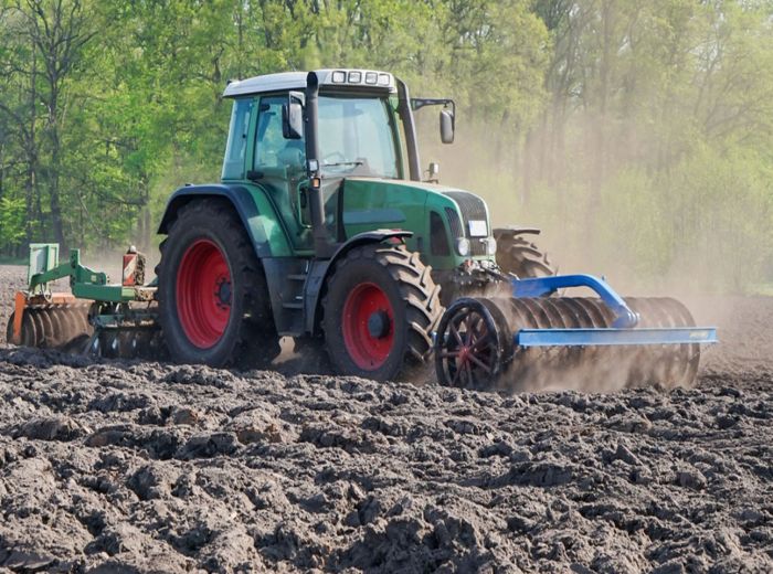 Ein Traktor pflügt ein Feld mit einem Pflug, symbolisiert durch GKB Bodenbearbeitung