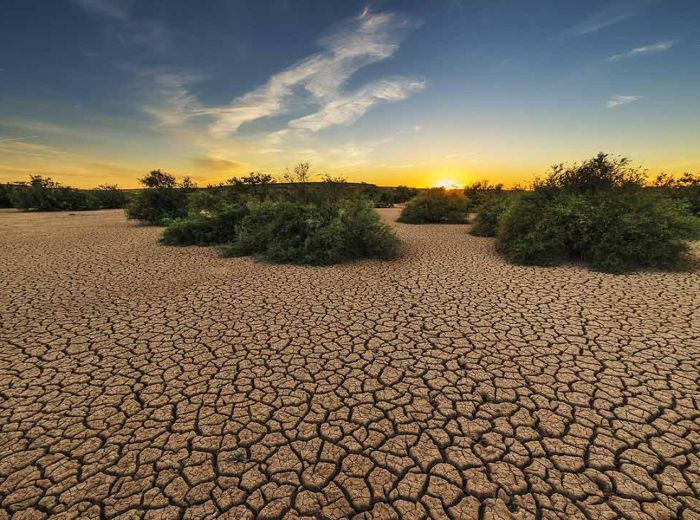 Der Sonnenuntergang beleuchtet eine trockene Wüstenlandschaft, die von Bodendegradation betroffen ist