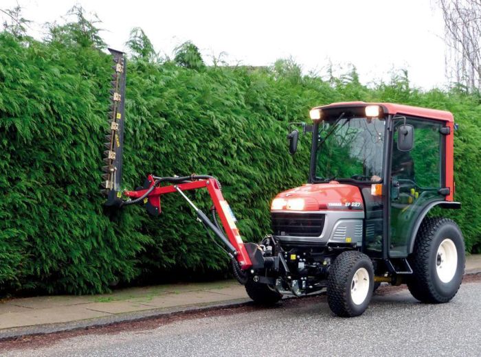 Ein Traktor von GMR Maskiner Elkaer steht neben einer Hecke geparkt