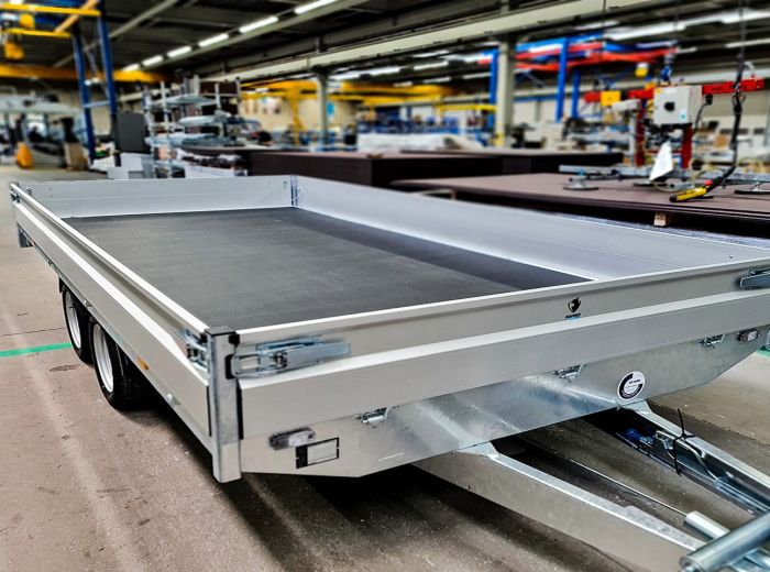 In einer Fabrik steht ein Hapert PKW Anhänger mit flachem Bett, bereit für den Transport von Materialien