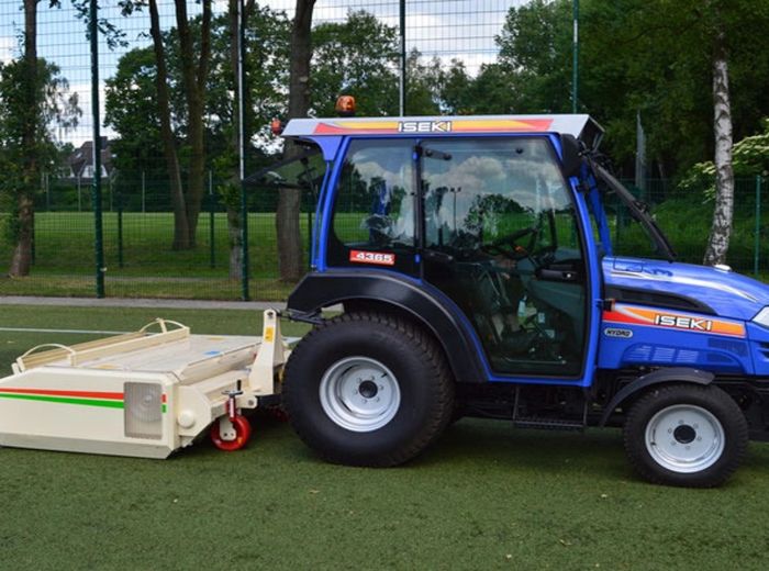 Auf einem Fußballfeld ist ein Traktor der Marke Hoerger Maschinen Iseki abgestellt.