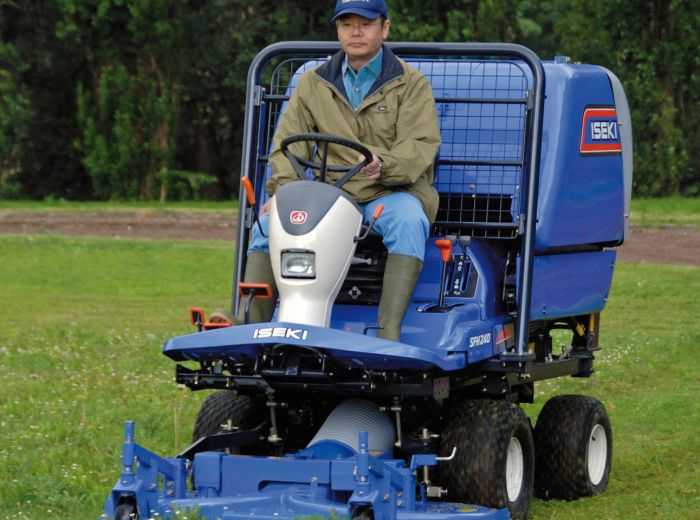 Ein Mann sitzt auf einem blauen Iseki Großflächenmäher SFH240 und steuert das Gerät auf einer grünen Wiese