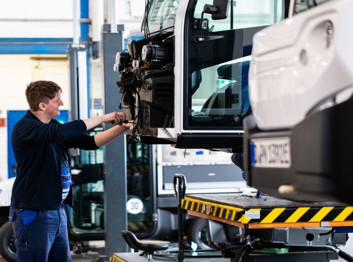 Ein Mann arbeitet in einer Garage an einem Fahrzeug, um Wartungsarbeiten durchzuführen