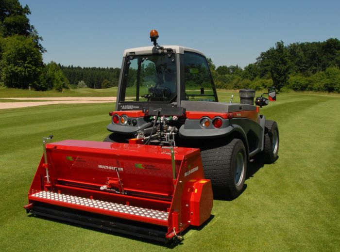 Kalinke Aebi Terratrac Traktor mit rotem Eimer, der auf einer Wiese steht