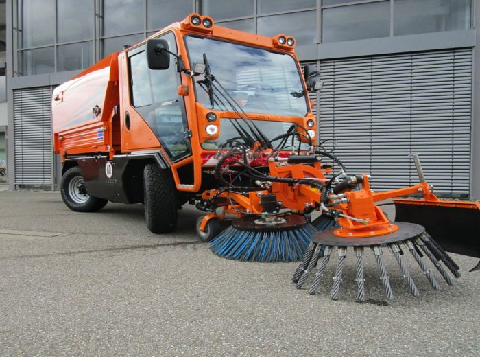 Großes orangefarbenes Kalinke Ladog Nutzfahrzeug mit einem Besen auf der Rückseite