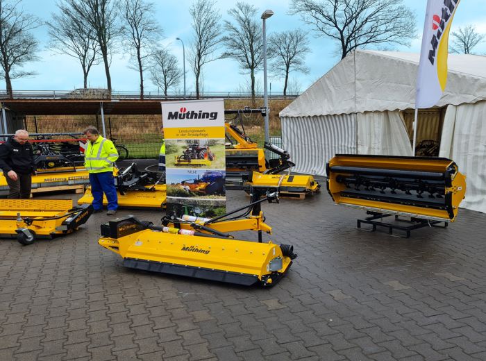 Ein Mann steht neben einer gelben Maschine auf dem Kommunaltag 2022, umgeben von Kunden und Interessierten