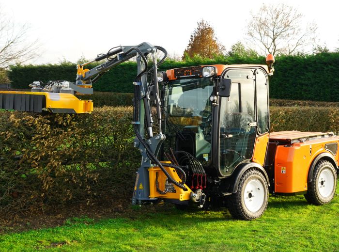 Ein Traktor mit einer Multihog Heckenschere schneidet präzise eine Hecke in einer ländlichen Umgebung