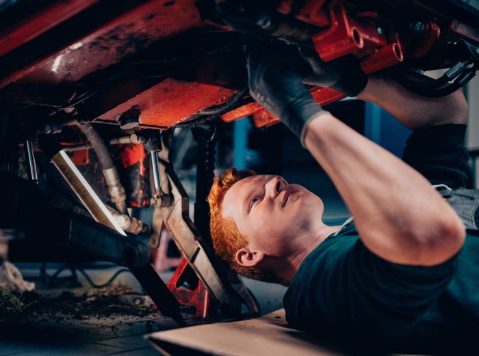 Ein Mitarbeiter in einer Werkstatt arbeitet an einem Fahrzeug und führt Reparaturen durch