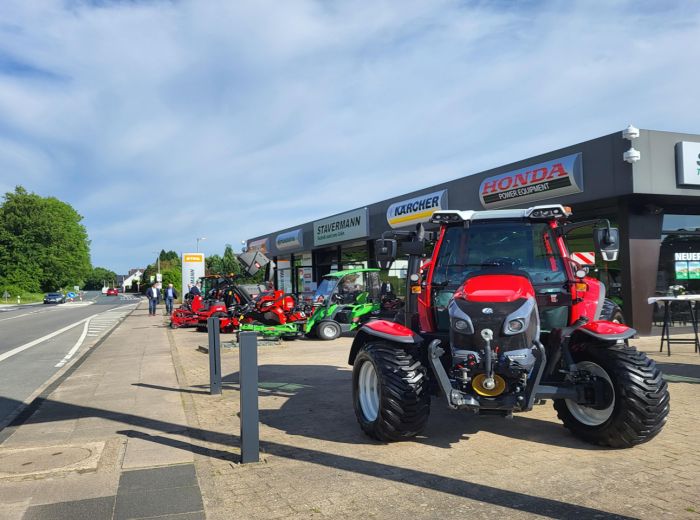 Ein roter Traktor steht am Straßenrand, symbolisch für die Neueröffnung 2024