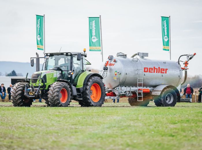 Ein Traktor zieht einen Tankwagen mit einem grünen und orangefarbenen Anhänger zum 70-jährigen Jubiläum von Oehler