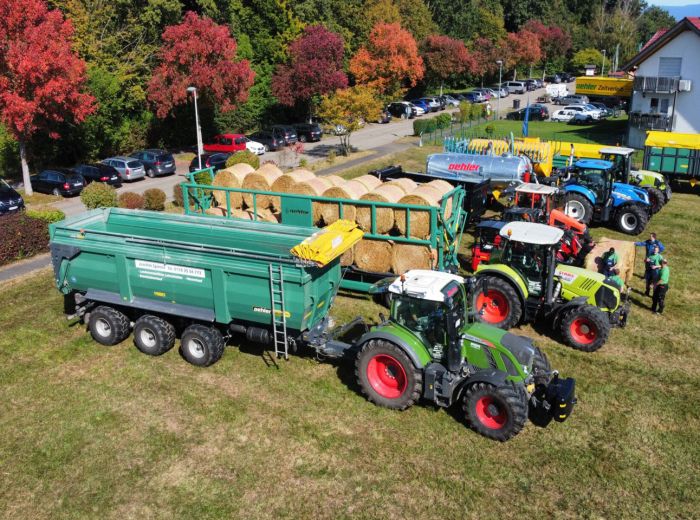 Eine Gruppe von Traktoren und Anhängern, die auf einem Feld während der Oehler Hausmesse geparkt sind