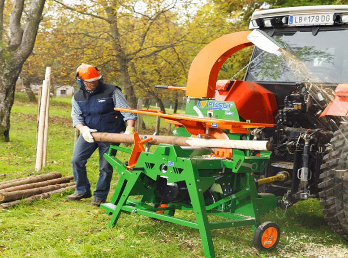 Ein Mann steht neben einem Traktor und einem Holzzerkleinerer, Modell Posch Schälprofi m1410e