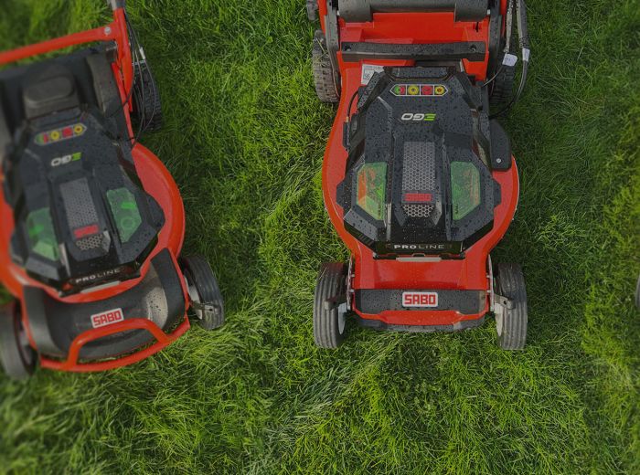 Drei rote Sabo-Rasenmäher stehen auf dem grünen Gras im Jahr 2023.