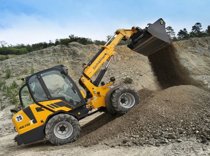 Der gelbe Schäffer 4670 T2 Bagger hebt Erde an und bereitet den Boden für Bauarbeiten vor