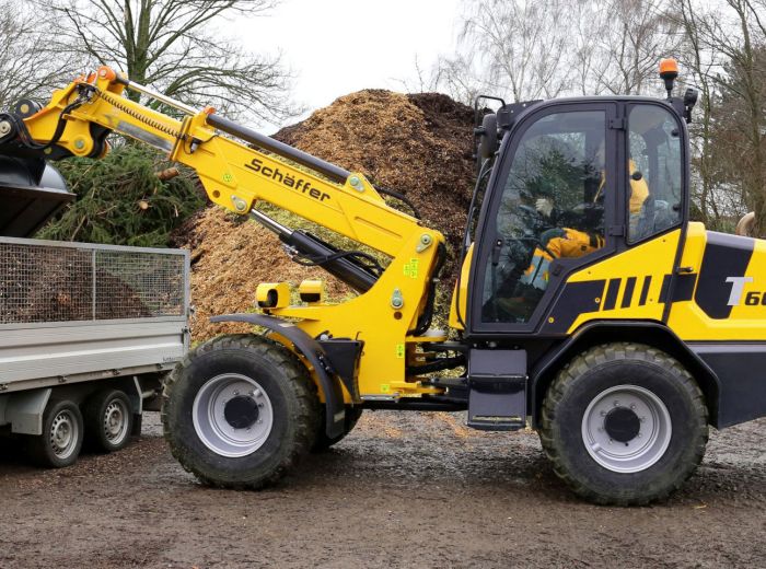 Gelbes Baufahrzeug Schäffer 6680 T mit einer Ladung Holz auf der Baustelle