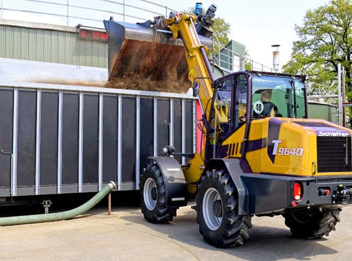 Gelber Schäffer Lader belädt sich mit Erde auf einem landwirtschaftlichen Gelände