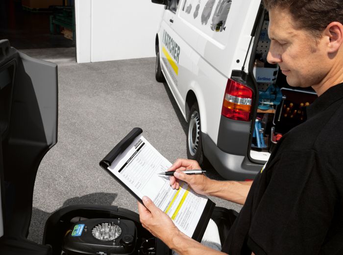 Ein Mann verfasst Notizen auf einer Checkliste, während er neben einem Van für den Kärcher-Service steht