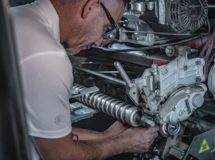 Ein Mann arbeitet an einem Motor in einer Garage, um das Toro Mähwerk zu warten und zu reparieren.