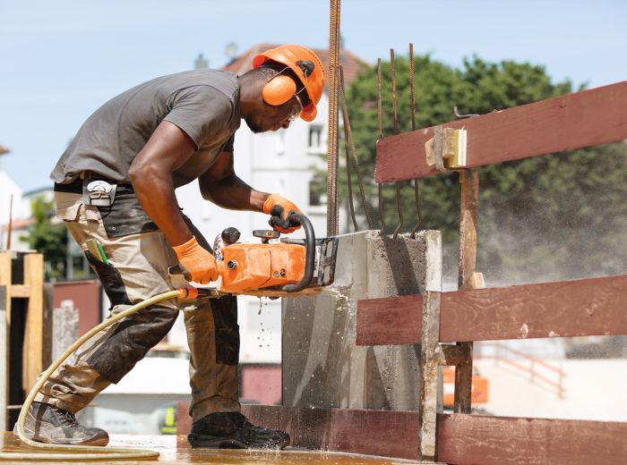 Ein Mann verwendet eine Stihl Kettensäge, um Holz zu bearbeiten und zeigt handwerkliches Geschick.