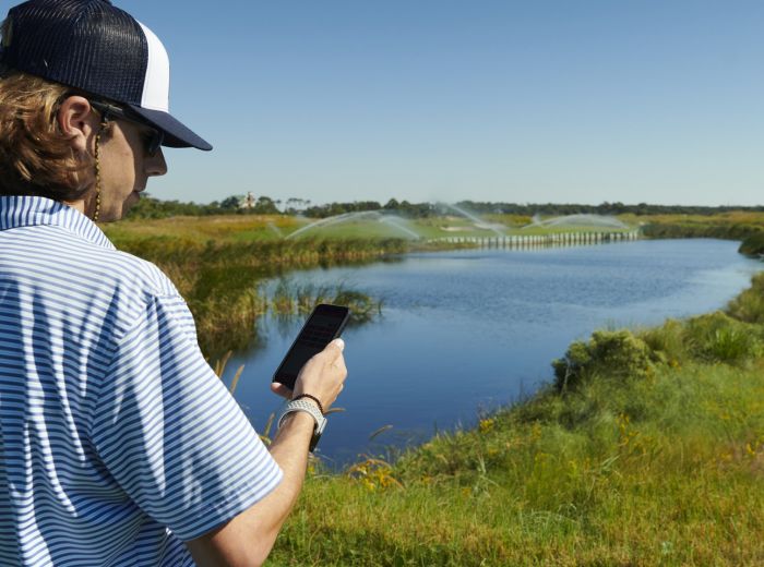 Ein Mann in South Carolina steht in einem Feld und nutzt sein Handy, um möglicherweise die Bewässerung zu steuern
