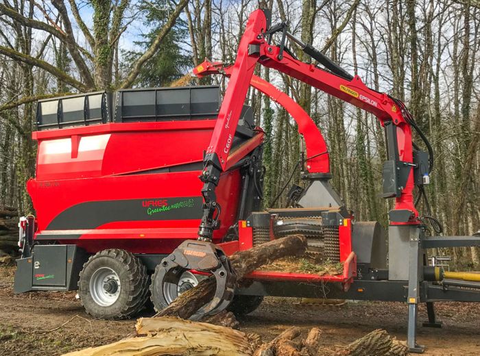 Ufkes Holzhäcksler: Eine rote Maschine belädt einen Lkw mit Holzstämmen.
