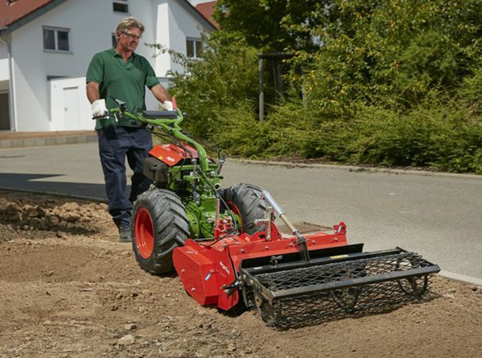 Ein Mann nutzt einen Traktor, um einen Garten zu bepflanzen und die Erde für die Pflanzen vorzubereiten.