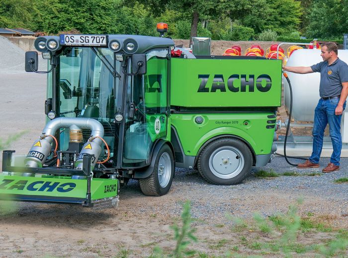 Ein Mann steht neben der grünen Maschine Zacho Egholm 2250 und zeigt Interesse an ihrer Funktionalität