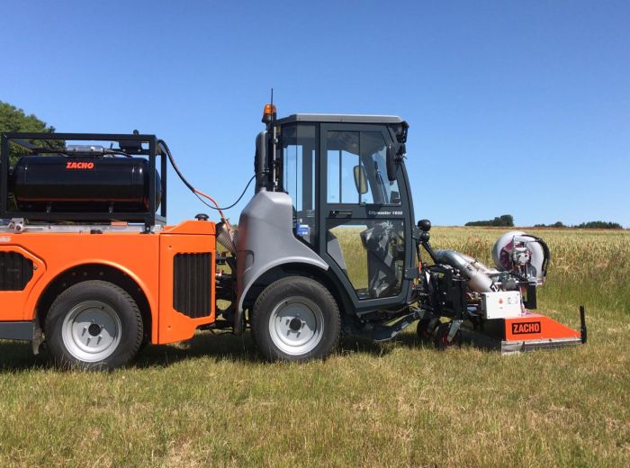Traktor mit großer Maschine auf dem Feld, seitliches Foto von Zacho, zeigt landwirtschaftliche Arbeit in Aktion